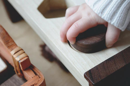 Hand eines Kleinkindes, was einen Holzbaustein aufnehmen möchte